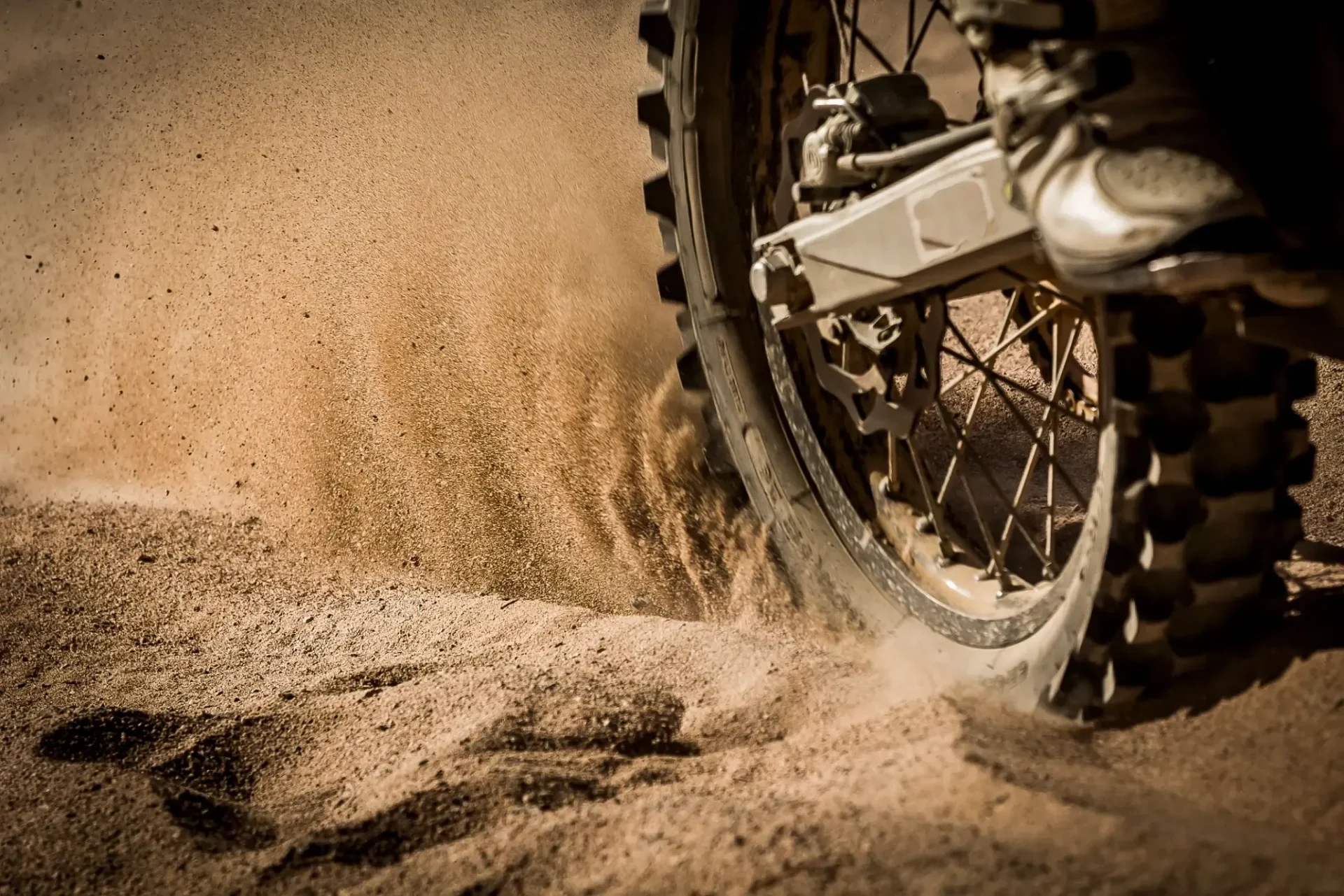 Dirt bike wheel kicking up sand